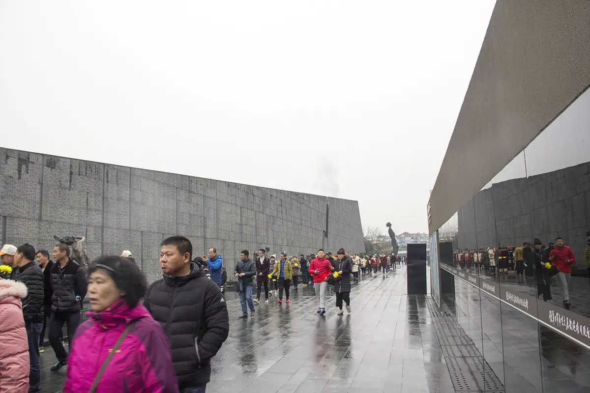 Visitors walking quietly along the grey stone exterior of the Memorial Hall